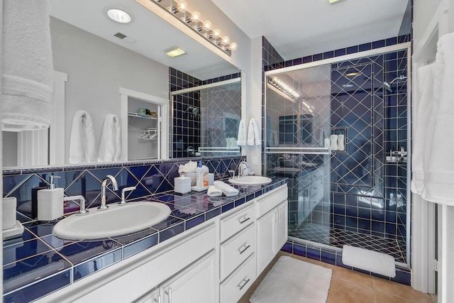 bathroom with a shower with door, vanity, tasteful backsplash, and tile patterned flooring