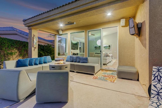 patio terrace at dusk with an outdoor living space with a fire pit