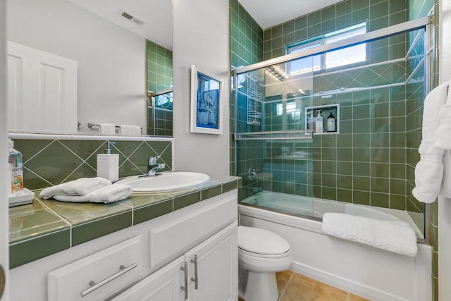 full bathroom with toilet, tasteful backsplash, bath / shower combo with glass door, tile patterned flooring, and vanity