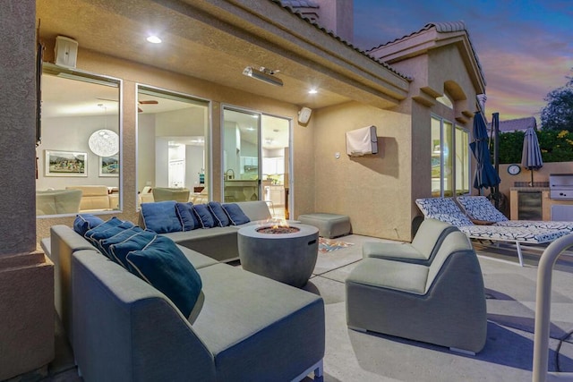 patio terrace at dusk with an outdoor living space with a fire pit