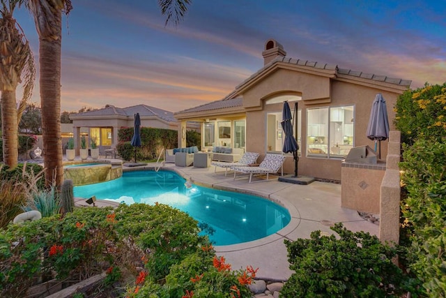 pool at dusk with a patio area, an outdoor kitchen, and outdoor lounge area