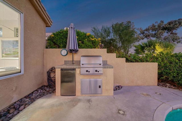 patio terrace at dusk with an outdoor kitchen and a grill