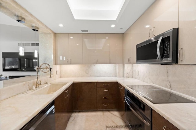 kitchen featuring tasteful backsplash, pendant lighting, sink, stainless steel appliances, and cream cabinets