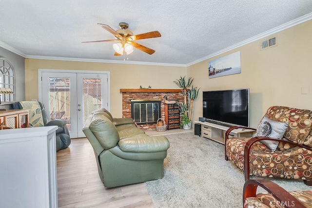 living room with a brick fireplace, a textured ceiling, ornamental molding, and french doors