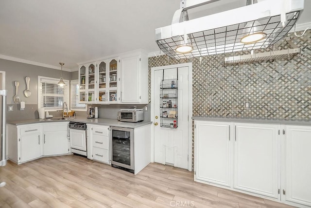 kitchen featuring white cabinetry, wine cooler, hanging light fixtures, ornamental molding, and sink