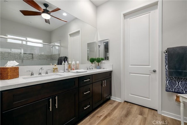 bathroom with ceiling fan, a shower with shower door, hardwood / wood-style floors, and vanity