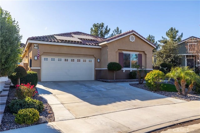 mediterranean / spanish home featuring a garage, solar panels, a tile roof, driveway, and stucco siding