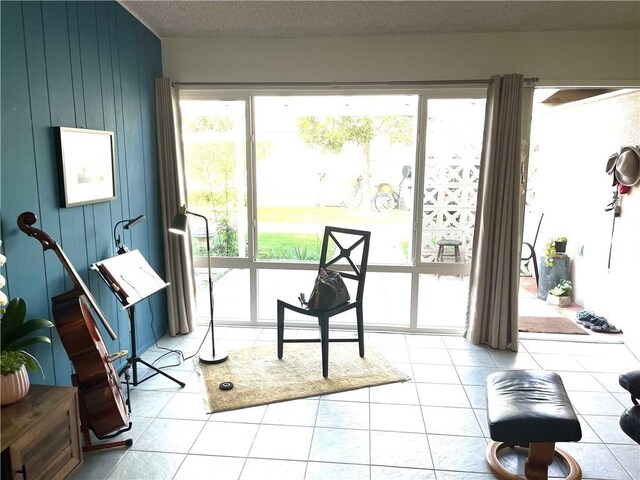 misc room featuring a textured ceiling, light tile patterned floors, and wood walls