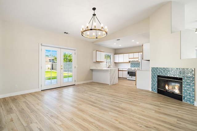 kitchen with lofted ceiling, white cabinetry, a fireplace, electric stove, and light wood-type flooring