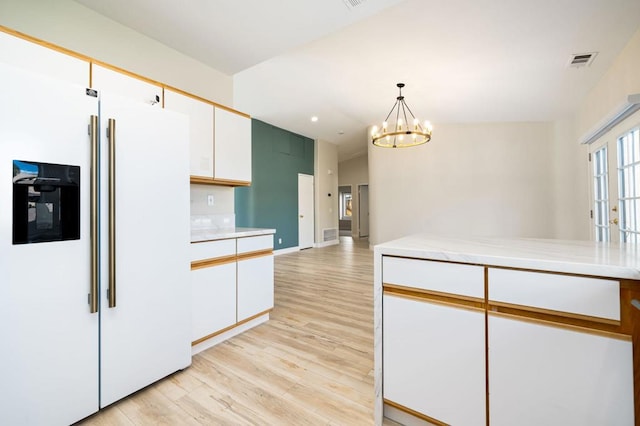 kitchen featuring decorative light fixtures, a notable chandelier, light hardwood / wood-style floors, white cabinetry, and white refrigerator with ice dispenser