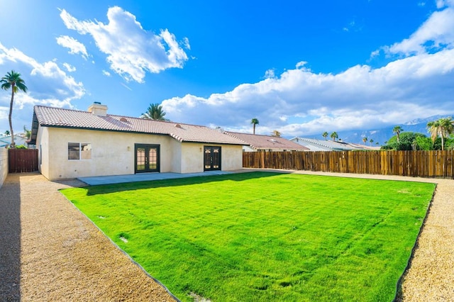 rear view of property with french doors, a patio area, and a yard