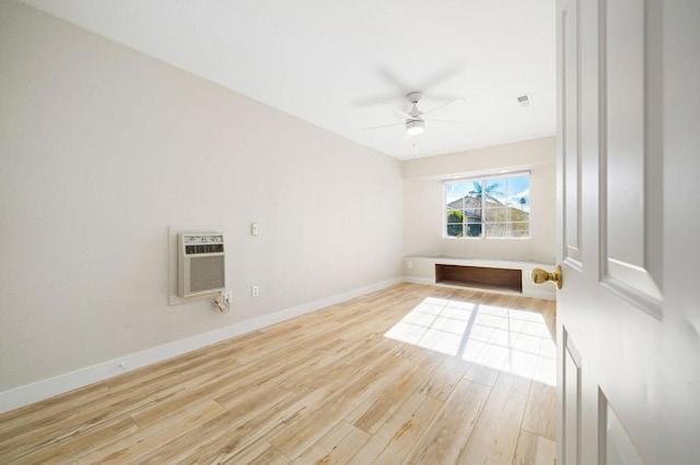 spare room featuring a wall unit AC, ceiling fan, and light wood-type flooring