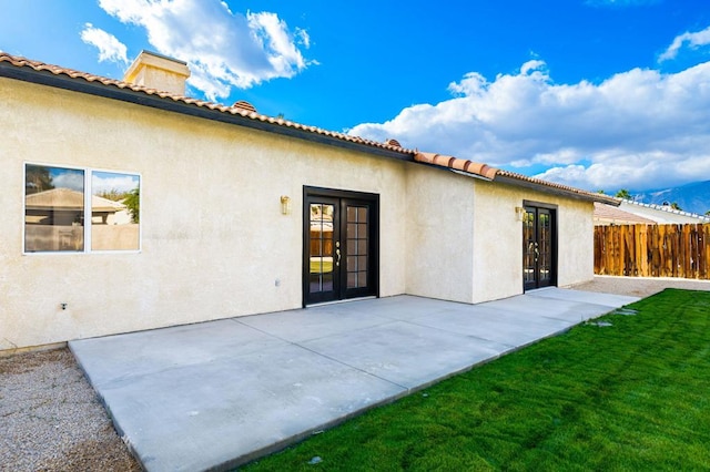 back of house with french doors, a lawn, and a patio