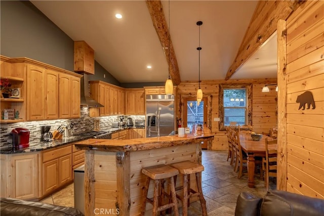 kitchen with wall chimney exhaust hood, decorative backsplash, light brown cabinets, pendant lighting, and stainless steel built in refrigerator