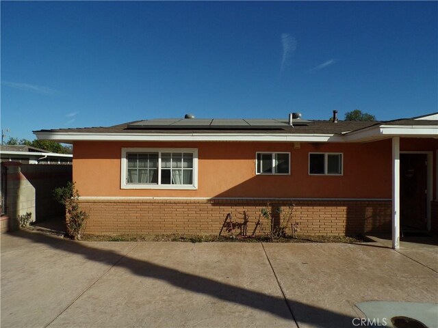 view of side of property with solar panels and a patio