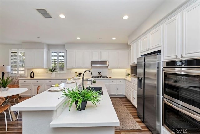 kitchen with a center island with sink, white cabinetry, dark wood-type flooring, and appliances with stainless steel finishes