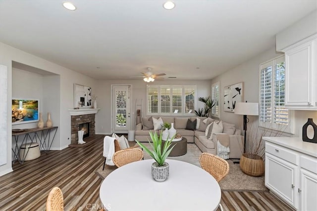 living room with ceiling fan and a stone fireplace