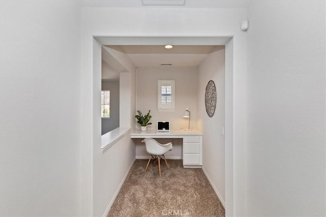 carpeted office featuring built in desk