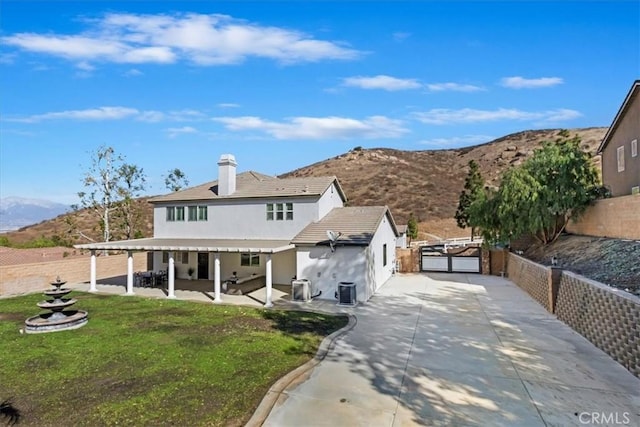 view of front of property with cooling unit, a front lawn, a mountain view, and a patio