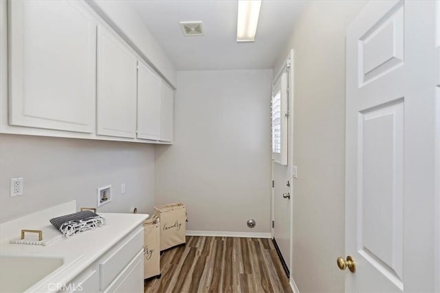 washroom featuring washer hookup, hardwood / wood-style floors, and cabinets