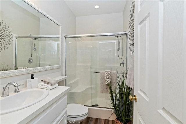 bathroom featuring toilet, hardwood / wood-style flooring, walk in shower, and vanity