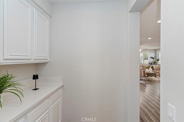 bar featuring white cabinets and light hardwood / wood-style flooring