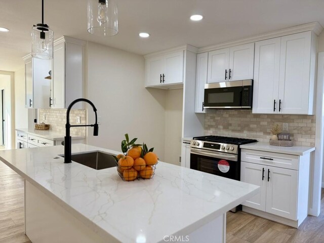 kitchen featuring sink, hanging light fixtures, white cabinets, and stainless steel appliances