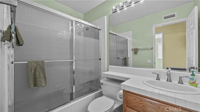 full bathroom featuring toilet, bath / shower combo with glass door, and vanity