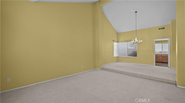 carpeted spare room featuring a chandelier and high vaulted ceiling