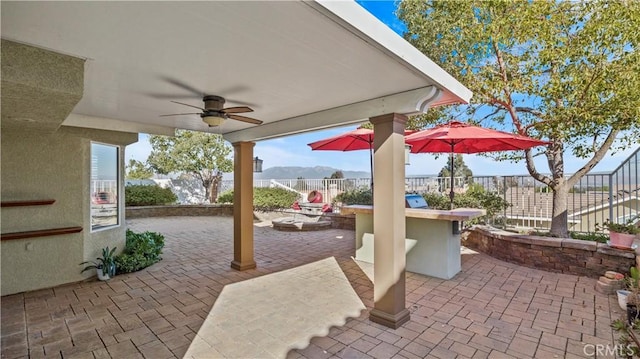 view of patio featuring ceiling fan, an outdoor bar, and a mountain view