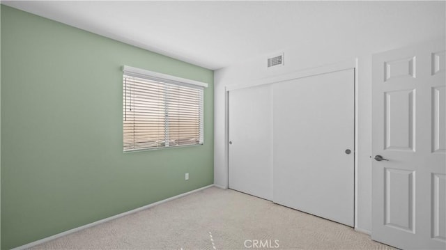 unfurnished bedroom featuring light colored carpet and a closet