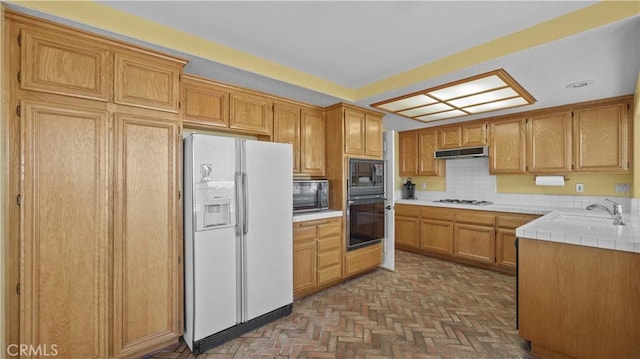 kitchen featuring sink, black appliances, tile countertops, and tasteful backsplash