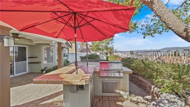 view of patio / terrace featuring a mountain view, ceiling fan, an outdoor bar, and area for grilling