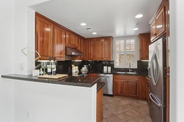 kitchen with appliances with stainless steel finishes, kitchen peninsula, sink, and decorative backsplash