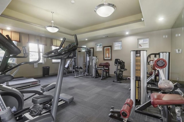 workout area with a raised ceiling and dark carpet