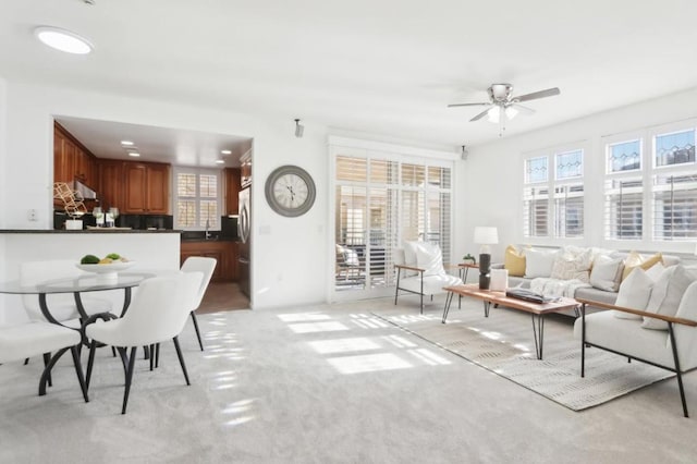 living room with sink, light colored carpet, and ceiling fan