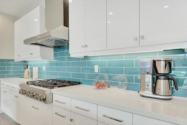 kitchen featuring stainless steel gas stovetop, decorative backsplash, wall chimney exhaust hood, and white cabinets