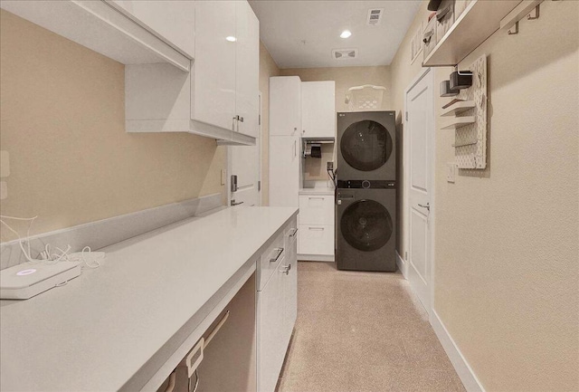 clothes washing area with stacked washer and dryer and cabinets