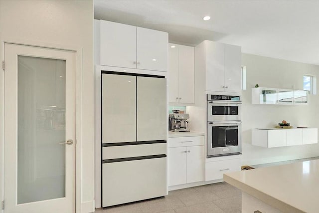 kitchen with white cabinetry, decorative backsplash, double oven, and white refrigerator