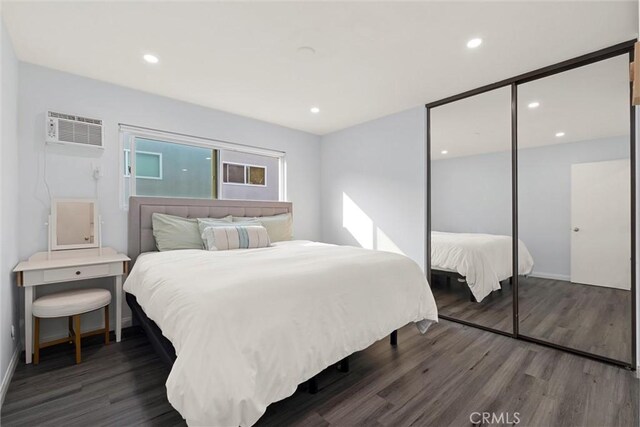 bedroom featuring a wall mounted AC, a closet, and dark hardwood / wood-style flooring