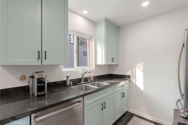 kitchen featuring dishwasher, refrigerator, dark stone countertops, sink, and dark hardwood / wood-style flooring