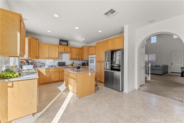 kitchen with sink, light tile patterned floors, light brown cabinetry, a kitchen island, and stainless steel fridge with ice dispenser