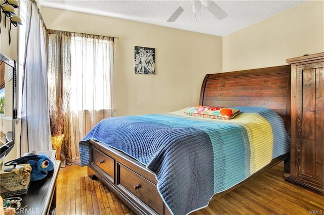 bedroom with a textured ceiling, dark wood finished floors, and a ceiling fan