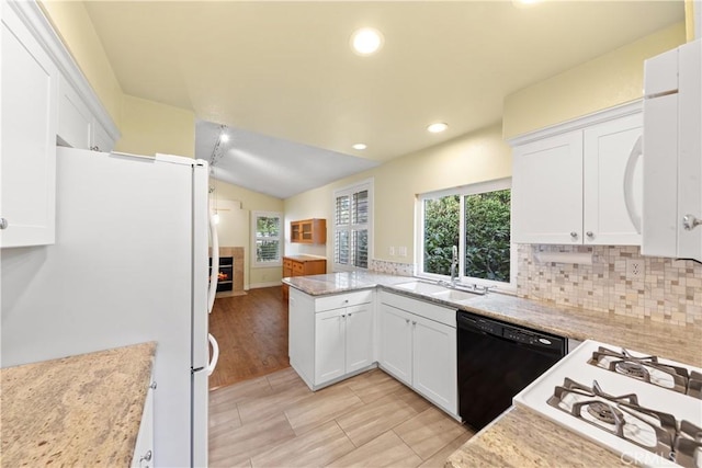 kitchen featuring dishwasher, sink, white fridge, and white cabinetry