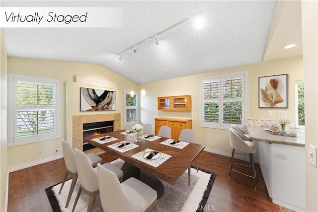 dining room with a textured ceiling, track lighting, lofted ceiling, and dark hardwood / wood-style floors