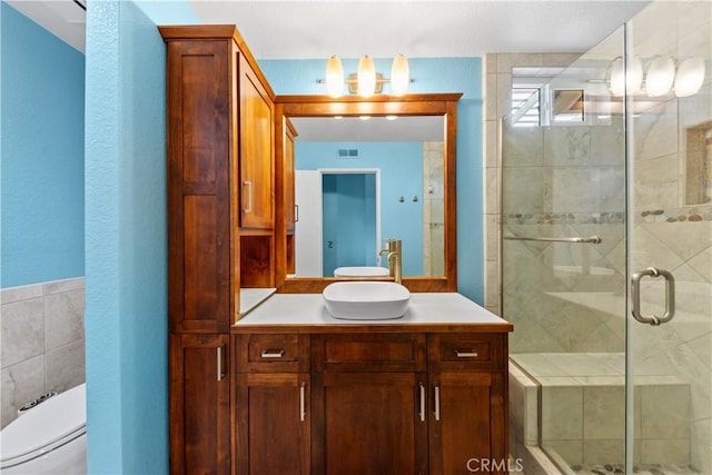 bathroom featuring a shower with shower door, toilet, and vanity