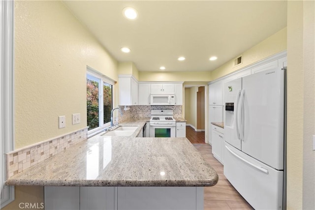 kitchen featuring kitchen peninsula, sink, white appliances, white cabinetry, and light stone countertops