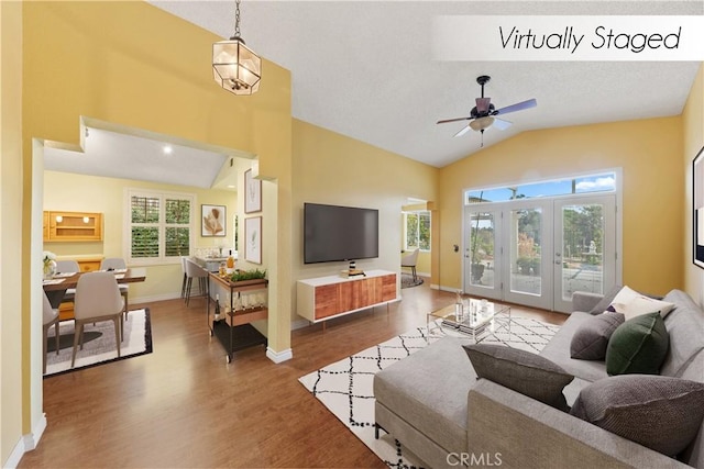 living room featuring hardwood / wood-style flooring, ceiling fan, french doors, and vaulted ceiling