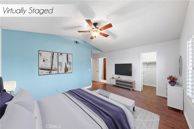 bedroom with ceiling fan, vaulted ceiling, a spacious closet, dark wood-type flooring, and a closet