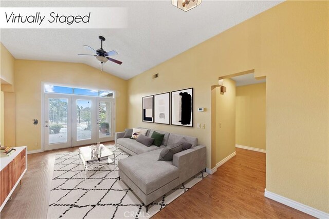 living room featuring ceiling fan, vaulted ceiling, french doors, and light wood-type flooring